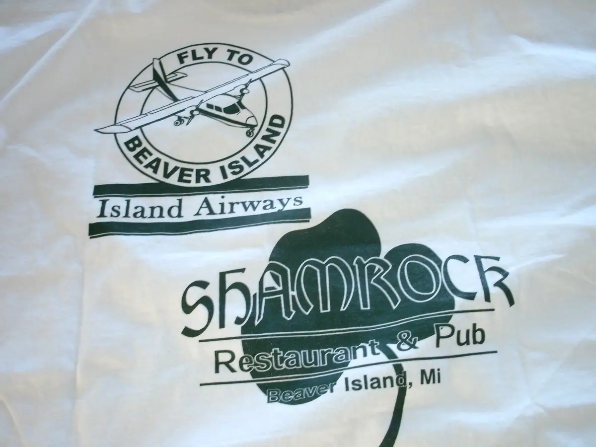 A white shirt displays a green airplane emblem and lettering for Island Airways and a restaurant and pub.