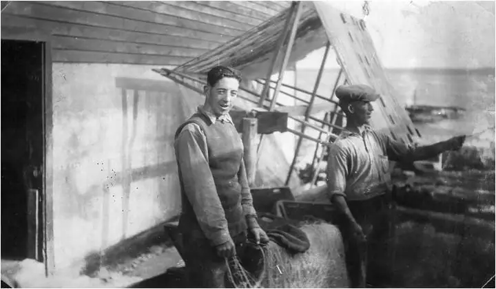 Two men work with a large fishing net beneath a wooden shelter.