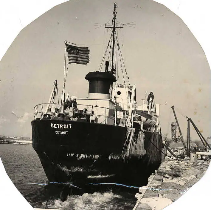 Black-and-white photograph of a large ship named DETROIT moored bow-first beside a pier.