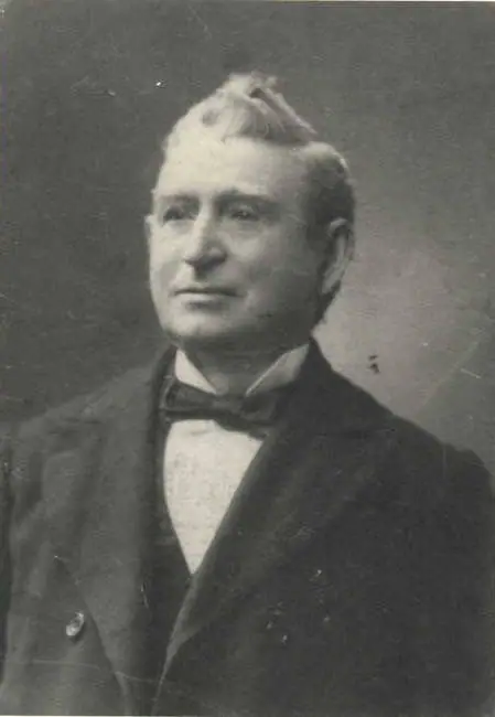 Monochrome portrait of a man in a dark suit and bow tie against a mottled background.