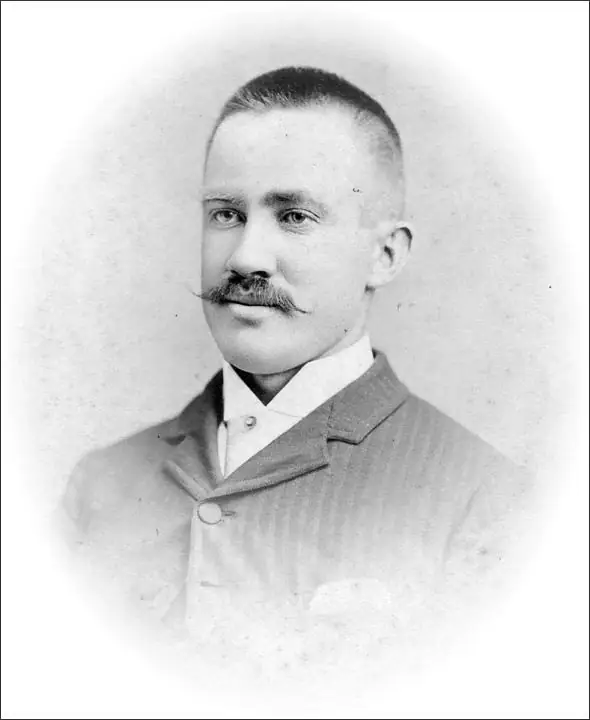 Black-and-white portrait of a mustached man in a high-collared shirt and suit jacket.
