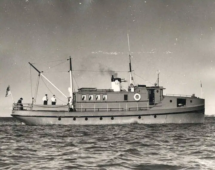 A small workboat carries several people across open water.