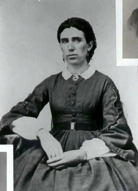 Black-and-white studio portrait of a seated woman wearing a dark dress with a white collar and cuffs.