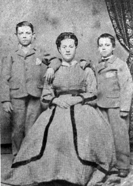 Black-and-white portrait of a seated woman between two boys in matching formal clothing.