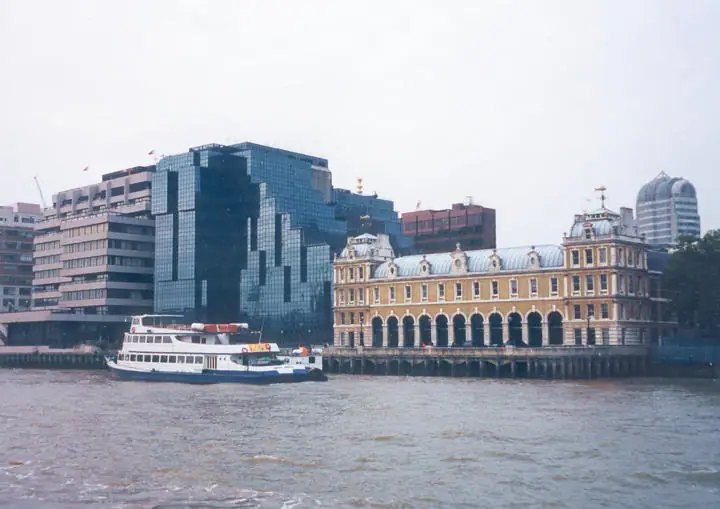 Passenger ferry on broad water before ornate historic and modern glass-fronted buildings.