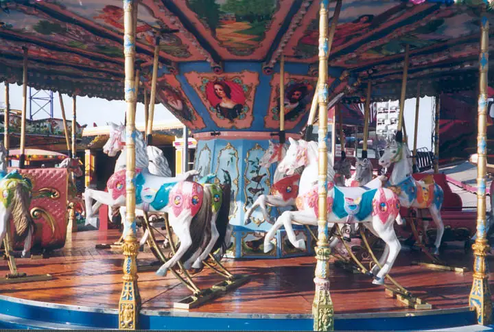 A brightly painted carousel with rows of decorative horses beneath a richly patterned canopy.