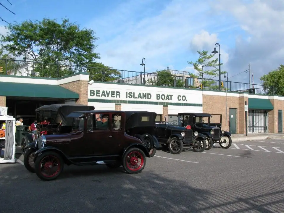 Vintage automobiles parked outside a brick building with a large company sign.