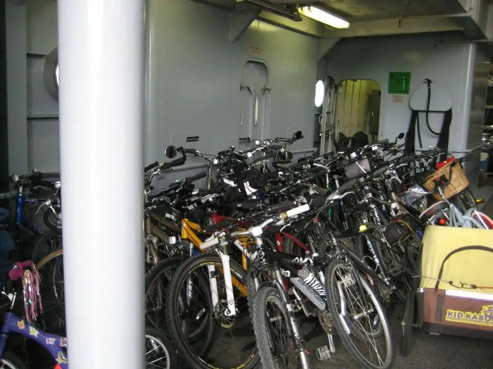 A crowded interior space is filled with bicycles, with a large white support column in the foreground.