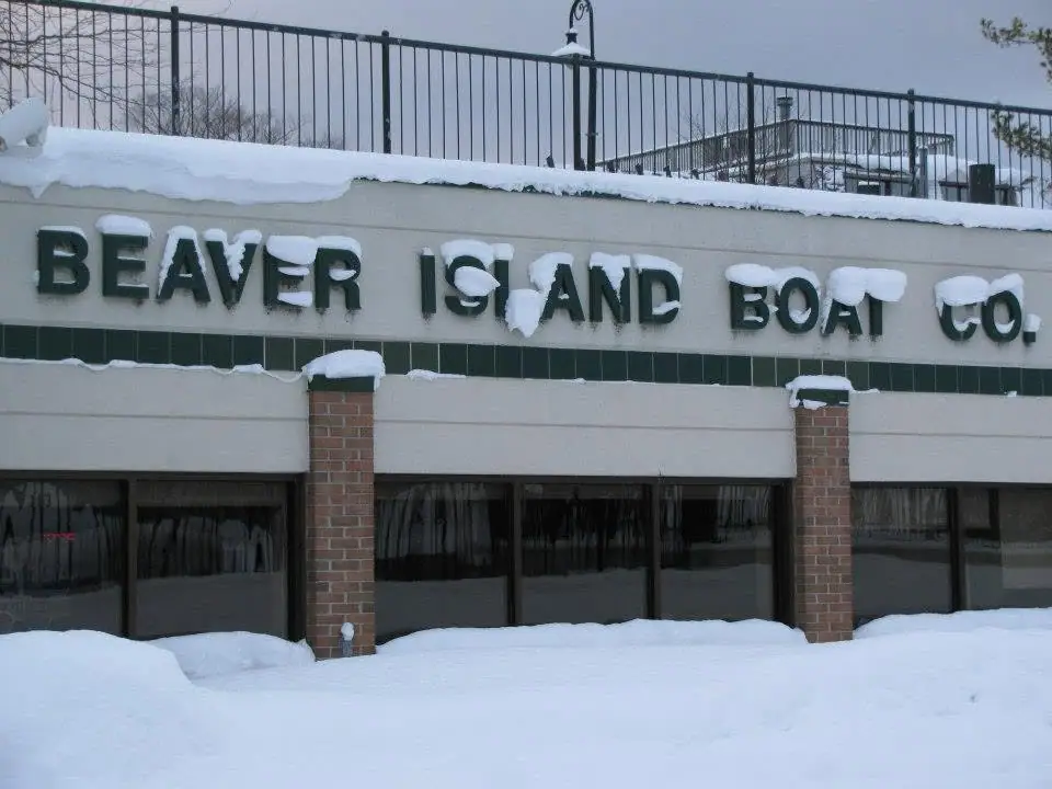 Snow-covered commercial building with a large sign reading “BEAVER ISLAND BOAT CO.”