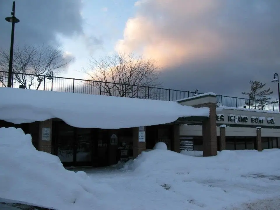 A snow-covered commercial building with a partially visible boat-company sign beneath a dramatic winter sky.