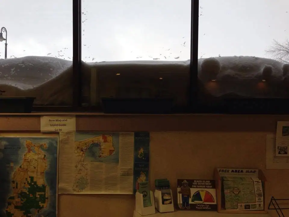 Interior display area with maps and brochures beneath windows blocked by heavy snow.