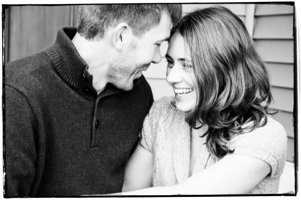 Black-and-white portrait of a smiling man and woman facing each other closely.