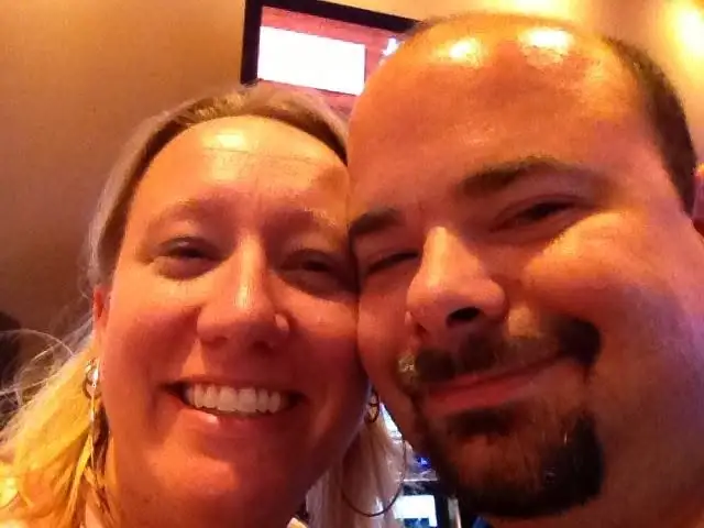 Close-up portrait of two adults smiling cheek to cheek indoors.
