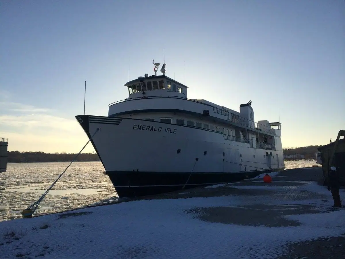 A large ferry named EMERALD ISLE is moored beside a snow-covered, ice-filled waterfront.
