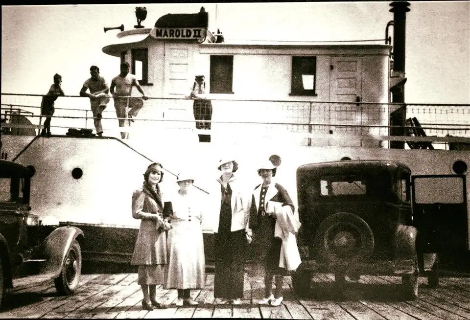Black-and-white photograph of people and vintage automobiles on the deck of the ferry Marold II.