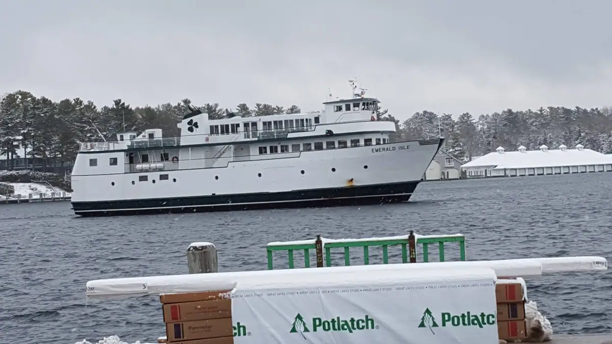 A white ferry passes a snowy waterfront, with Potlatch-wrapped boxes in the foreground.