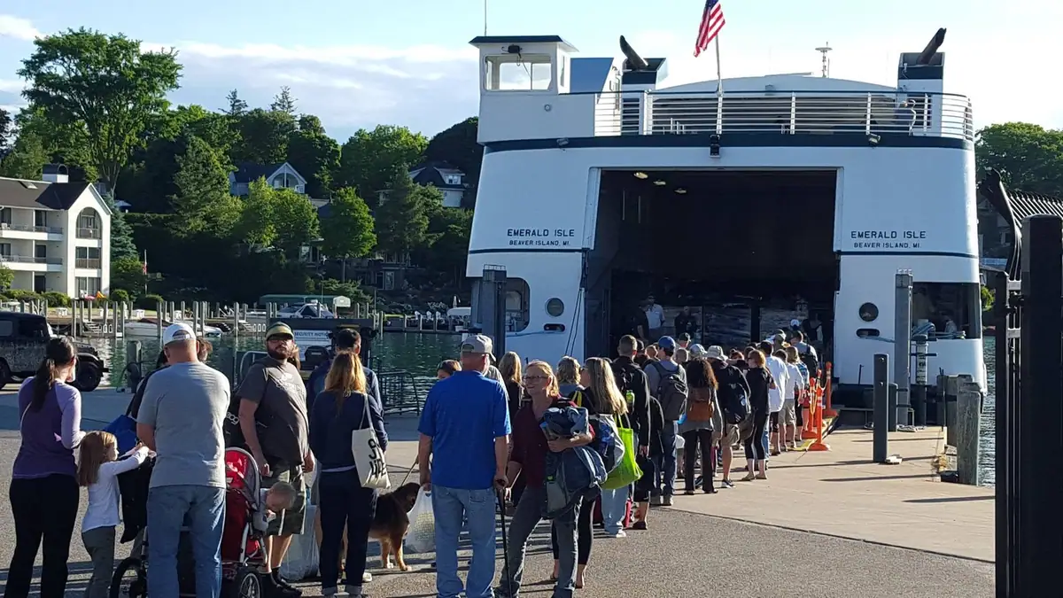 A ferry is docked as a long line of passengers waits to board.