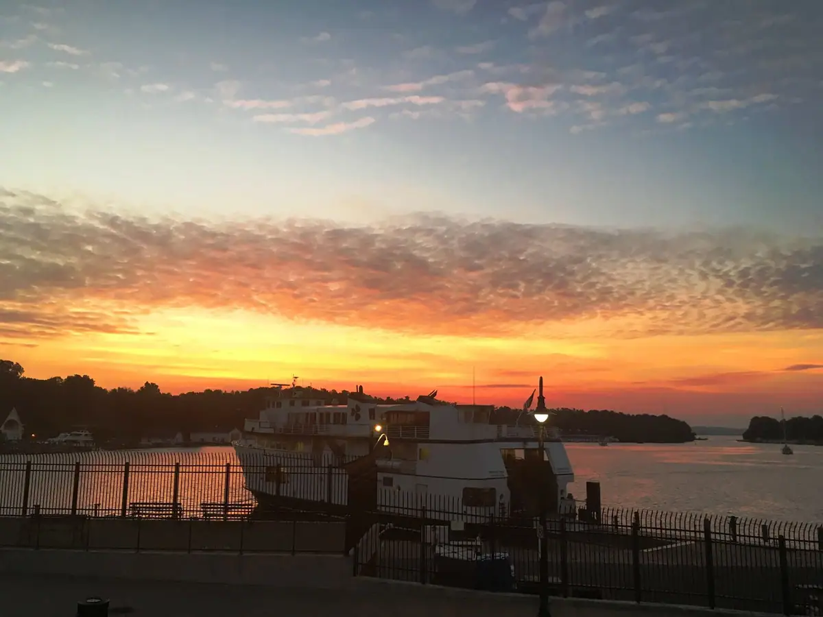 A white ferry sits beside a pier beneath a vivid orange sunset.