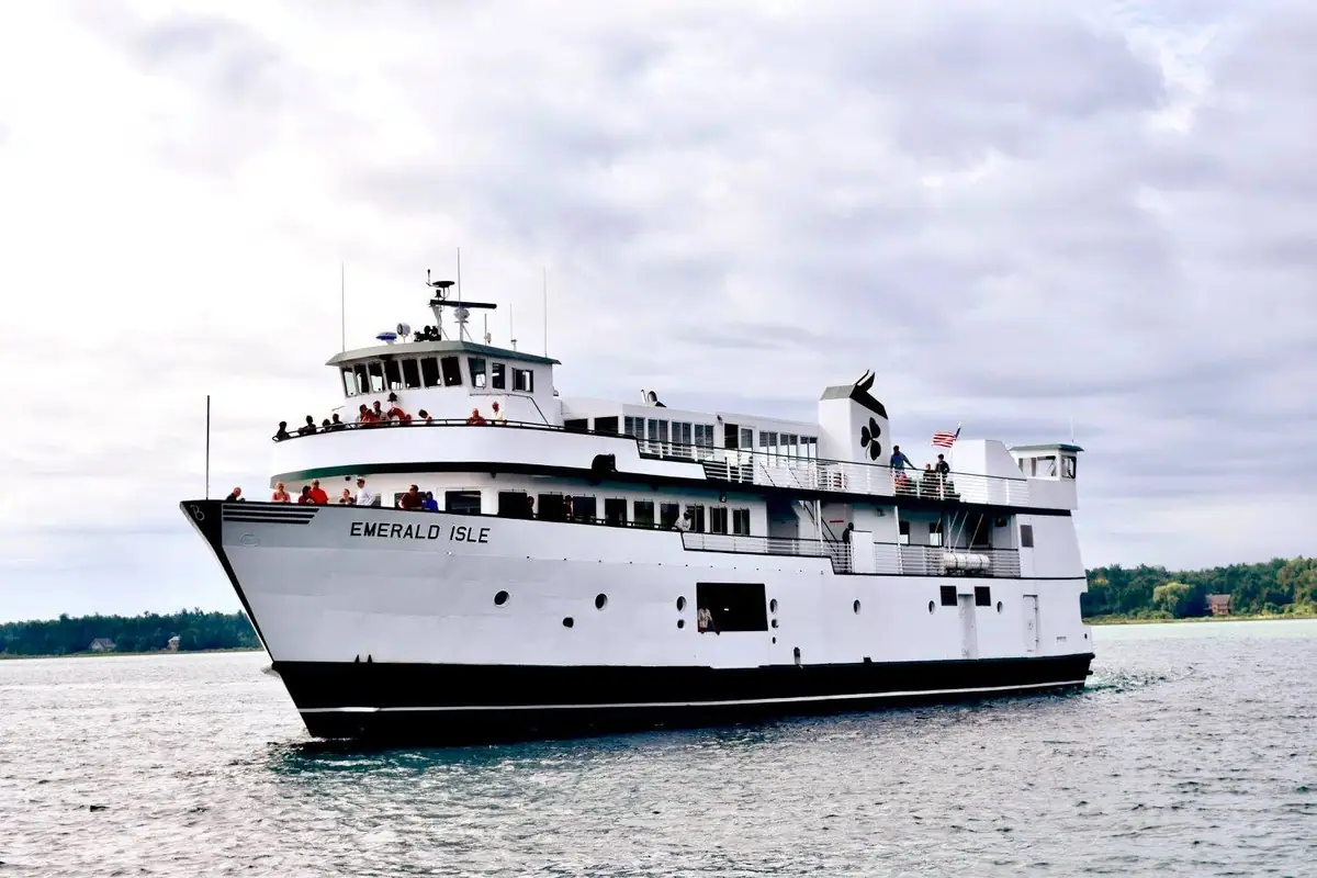 White passenger ferry marked “EMERALD ISLE” traveling across choppy water with people on its decks.