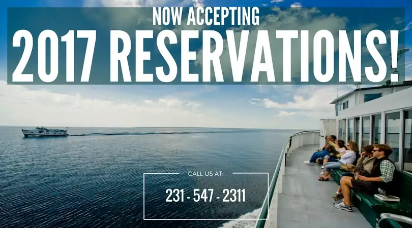 Passengers sit on the open deck of a ferry while another ferry travels across the water nearby.