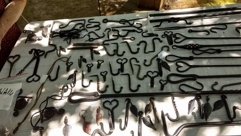 Assorted dark metal hooks, rods, loops, and leaf- and heart-shaped ornaments arranged on a tabletop.