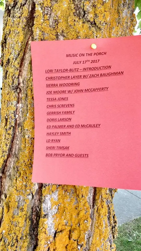 A red music-event program is pinned to a lichen-covered tree trunk.