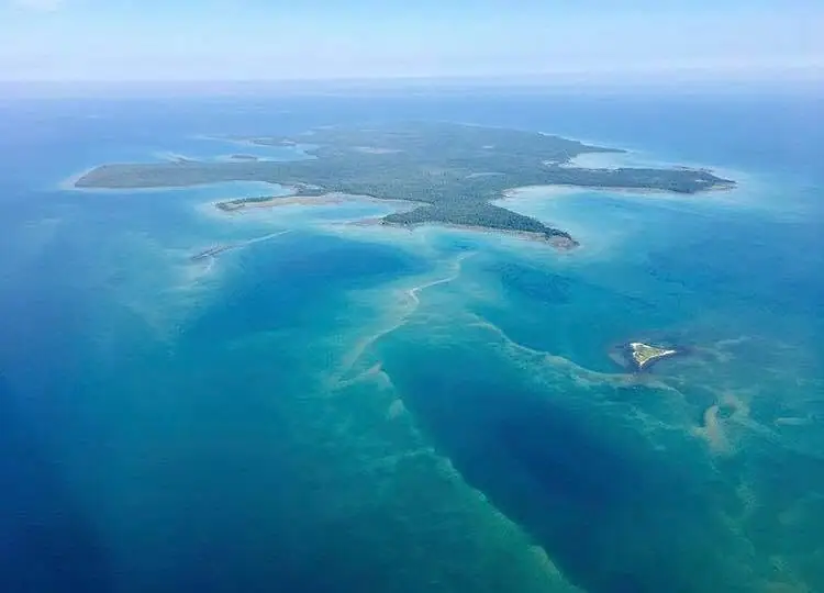 Aerial photograph of wooded landmasses, narrow shorelines, and turquoise water.