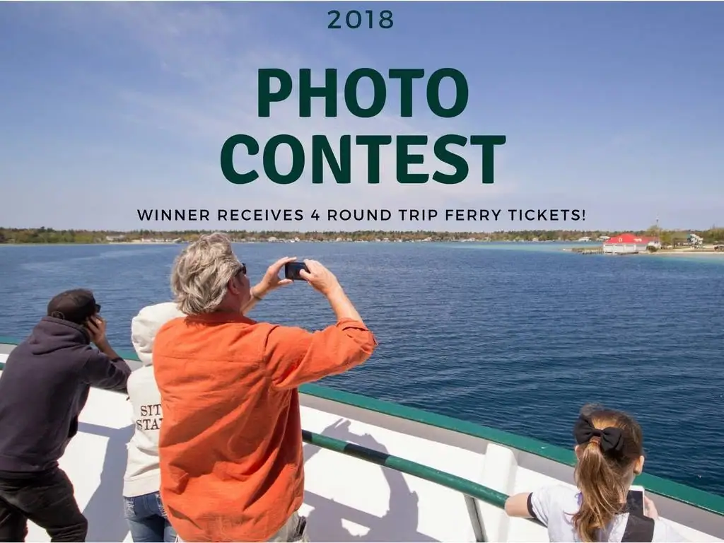 People photograph a broad waterfront from a boat deck beneath a large photo contest announcement.