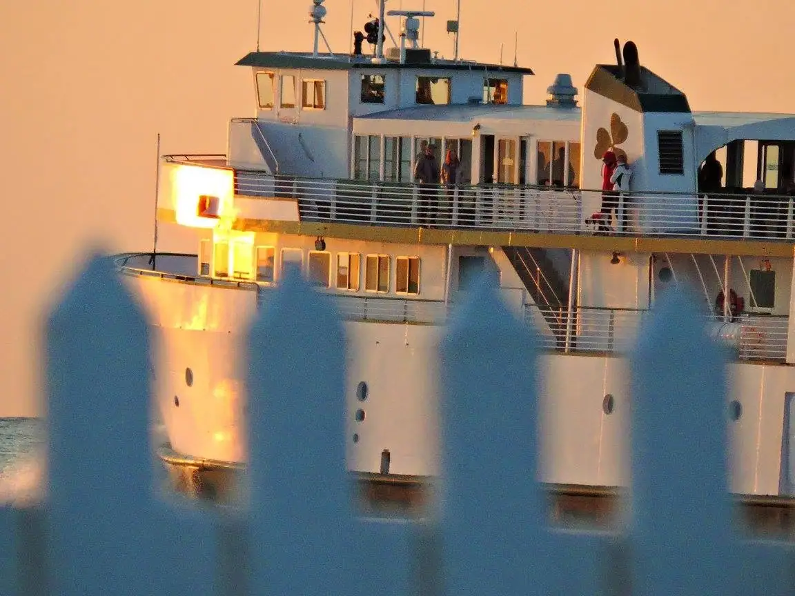 A large white passenger ferry glows in warm evening light behind an out-of-focus blue foreground.