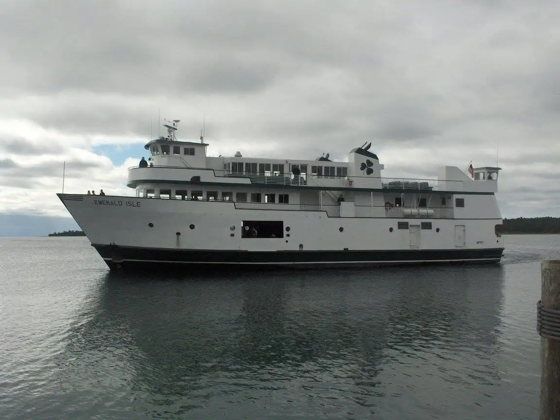 A white passenger ferry named EMERALD ISLE moves across gray water beneath a cloudy sky.