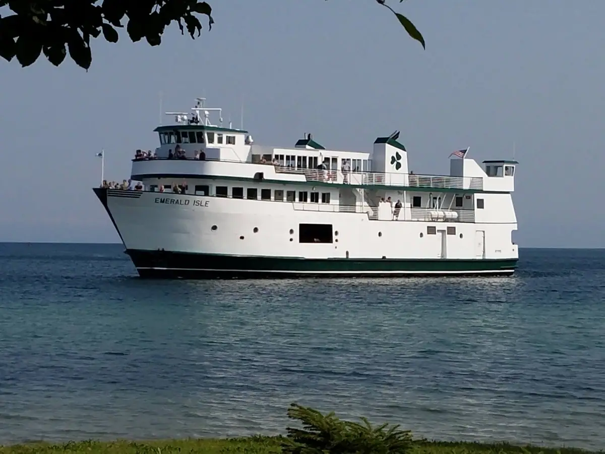 White multi-deck ferry with green trim and passengers traveling across open water.
