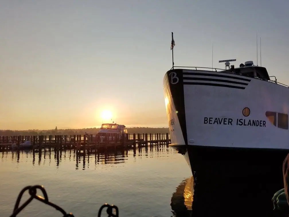 A white-and-black ferry named BEAVER ISLANDER sits beside a pier at sunset.