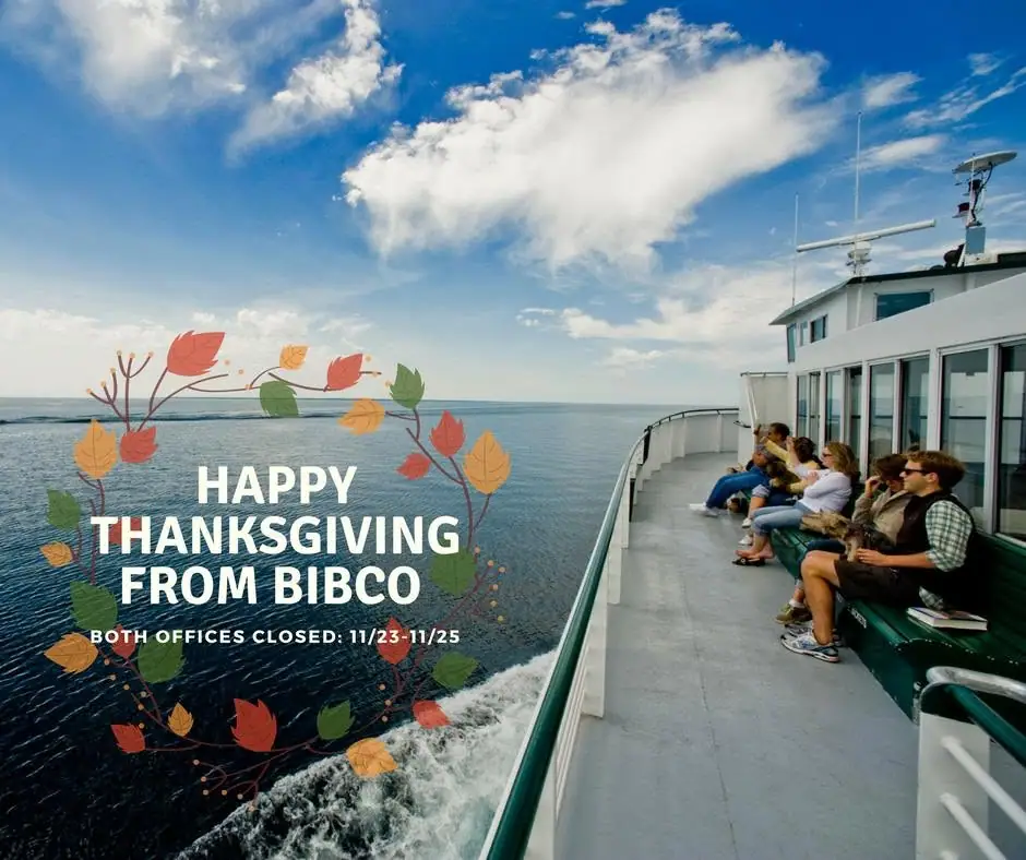 Passengers sit on the open deck of a ferry beside a broad expanse of water, with a holiday greeting overlaid.