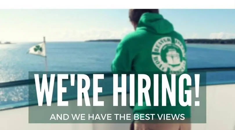 A person in a green hoodie looks over blue water beneath a bold hiring message.