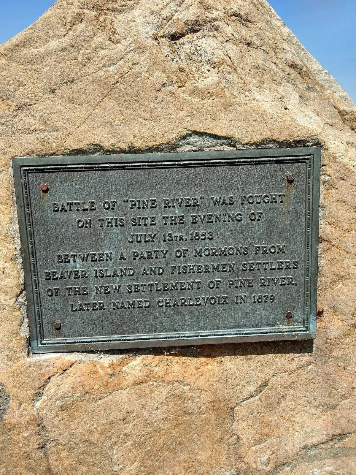 A historical metal plaque mounted on a large rough rock.