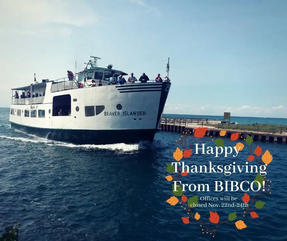 A white passenger ferry passes a pier with people on deck and a Thanksgiving greeting overlaid at lower right.