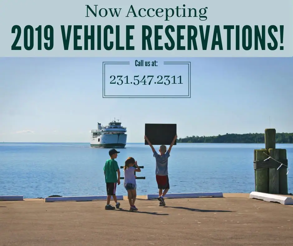 Three children stand on a dock as a ferry approaches, beneath a vehicle-reservation announcement.