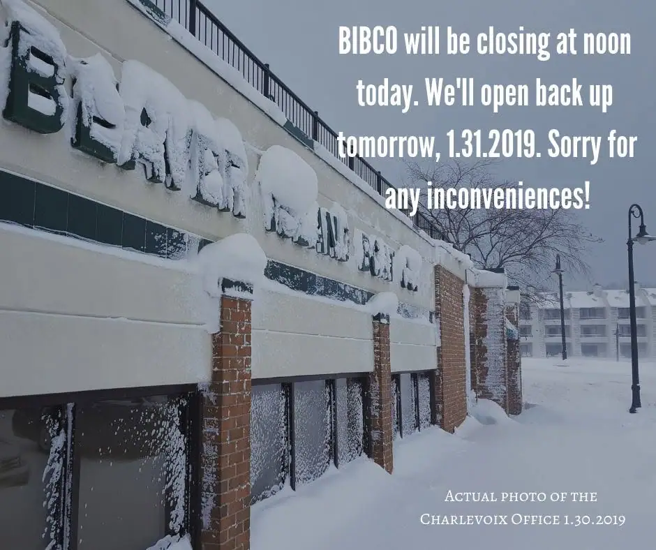 Snow-covered commercial office building with printed closure notice and deep snow along the sidewalk.