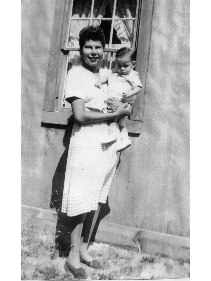 Black-and-white portrait of a woman holding a small child outside a building.