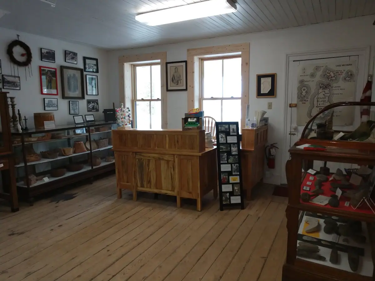 Museum room with wooden display cases, framed pictures, a central counter, and a wall map.