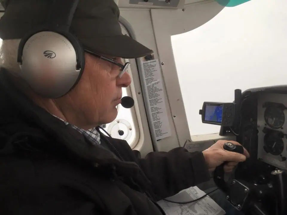 A pilot wearing a headset operates the controls inside an aircraft cockpit.