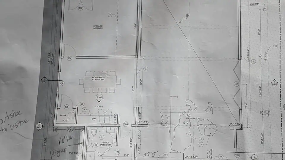 Photographed architectural floor plan showing labeled rooms, fixtures, measurements, and handwritten annotations.