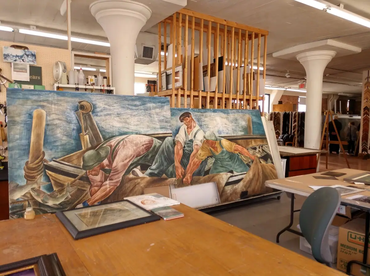 Two mural panels depicting fishermen handling fish in a bright workshop interior.