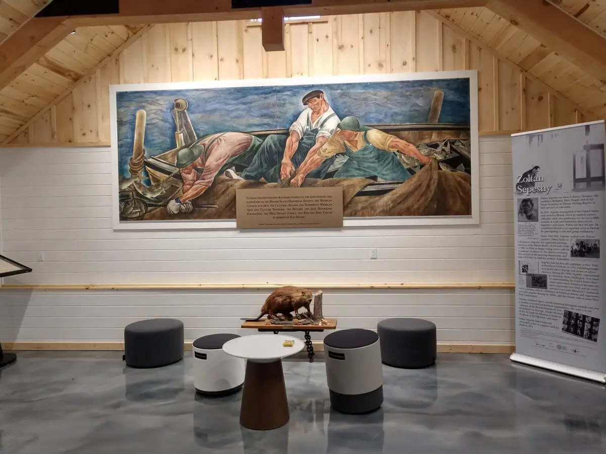 Gallery interior with a large mural of three fishermen working aboard a wooden boat.