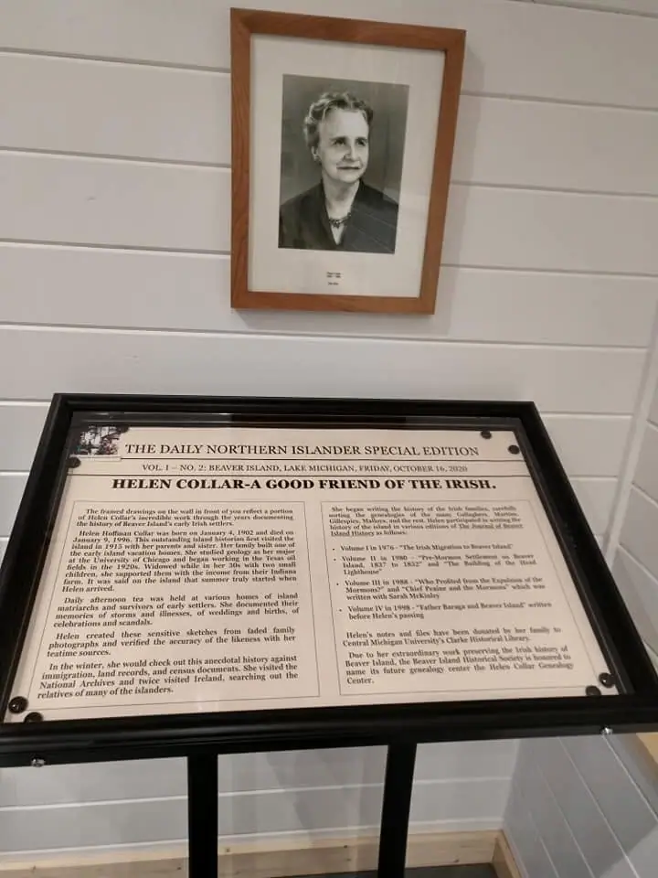 A framed black-and-white portrait hangs above a framed printed historical display panel.