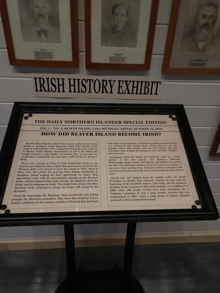 An indoor Irish history exhibit with framed portraits and a large printed display panel on a stand.