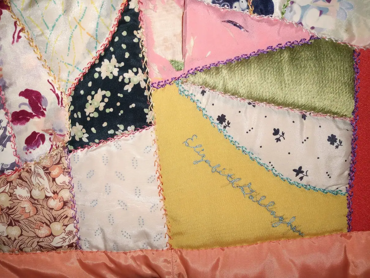 Close-up of a colorful patchwork quilt with patterned fabric pieces and decorative stitched borders.