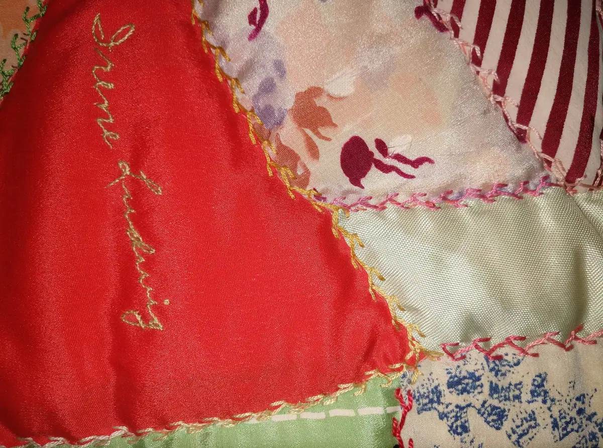 Close-up of layered fabric panels with gold embroidery and colorful patterned cloth.