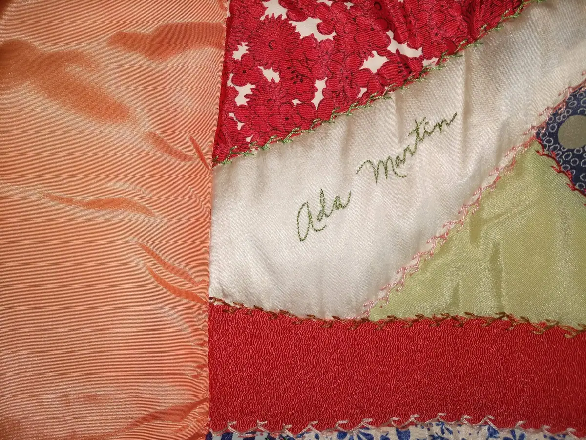Close-up of a patchwork quilt with floral fabric and green embroidery on a central white panel.