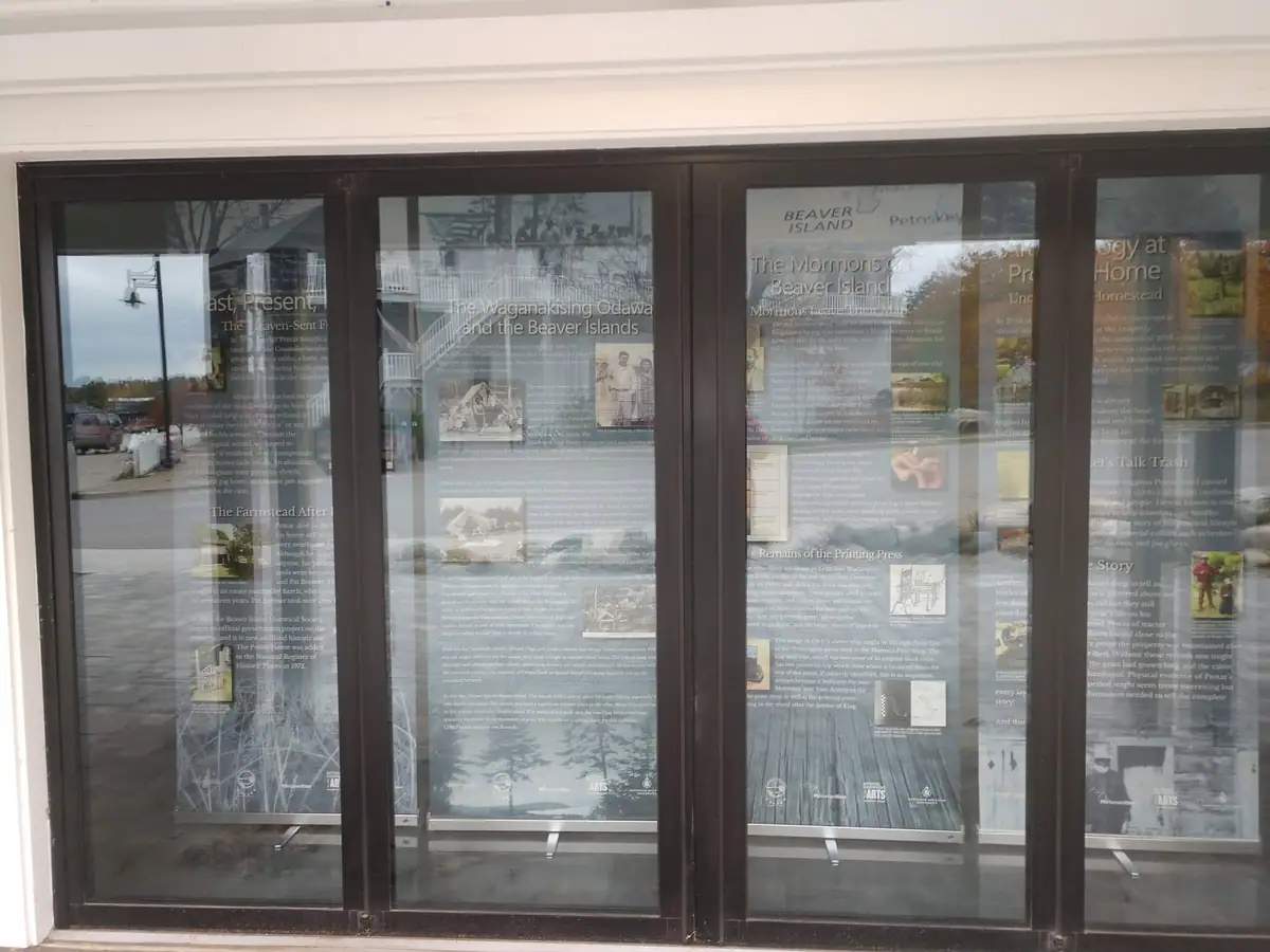 Four glass display windows present historical exhibit panels, photographs, and text behind reflective panes.